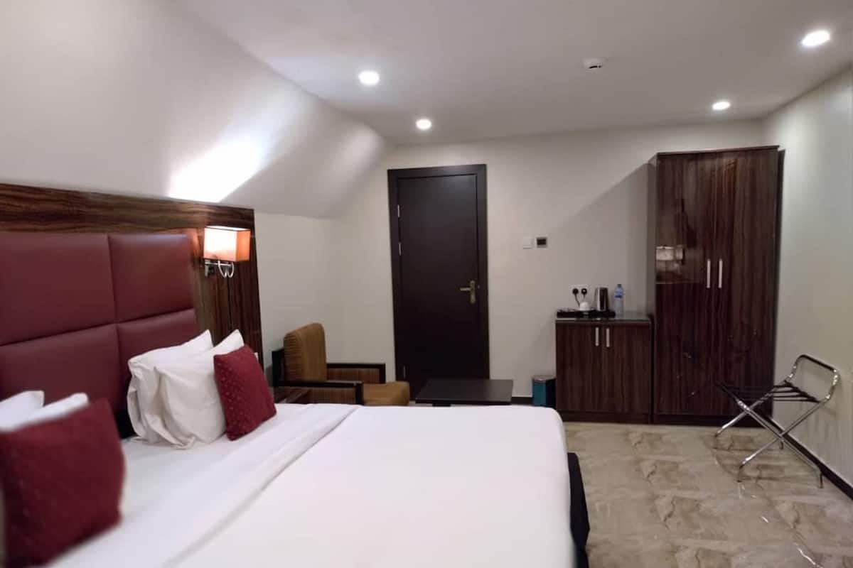 A hotel room with a bed, a desk, a chair, a wardrobe, and a door.