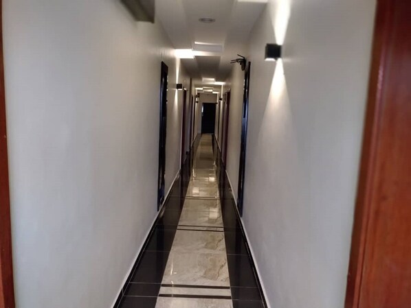 Un long couloir étroit, doté d’un sol carrelé et de murs blancs.