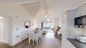 A spacious living area with a dining table, chairs, a sofa, and a television.