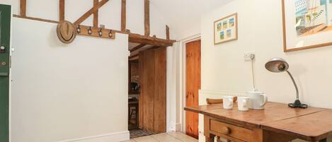 A cozy kitchen with wooden beams, a dining table with stools, and a hanging hat.