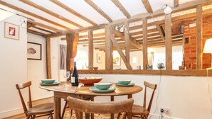 A dining area with a wooden table, four chairs, and a large mirror reflecting the room. - 48 Polecat Cottages (Lewes)