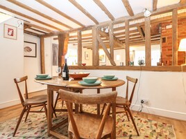 A dining area with a wooden table, four chairs, and a large mirror reflecting the room.