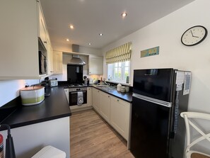 A modern kitchen with a black refrigerator, a stove, and a sink.