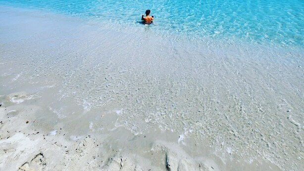 A beach with clear turquoise water and a person swimming. - Spacious holiday home near the sea with courtyard perfect for families & friends (Cooperativa Phiniscollis)