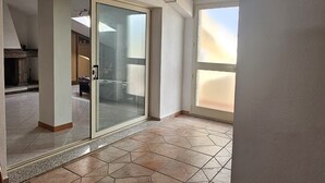 An interior space with a tiled floor, a glass door leading to another room, and a ceiling with exposed beams. - Spacious holiday home near the sea with courtyard perfect for families & friends (Cooperativa Phiniscollis)