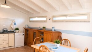A kitchen with a dining table, chairs, and a window. - Spacious holiday home near the sea with courtyard perfect for families & friends (Cooperativa Phiniscollis)