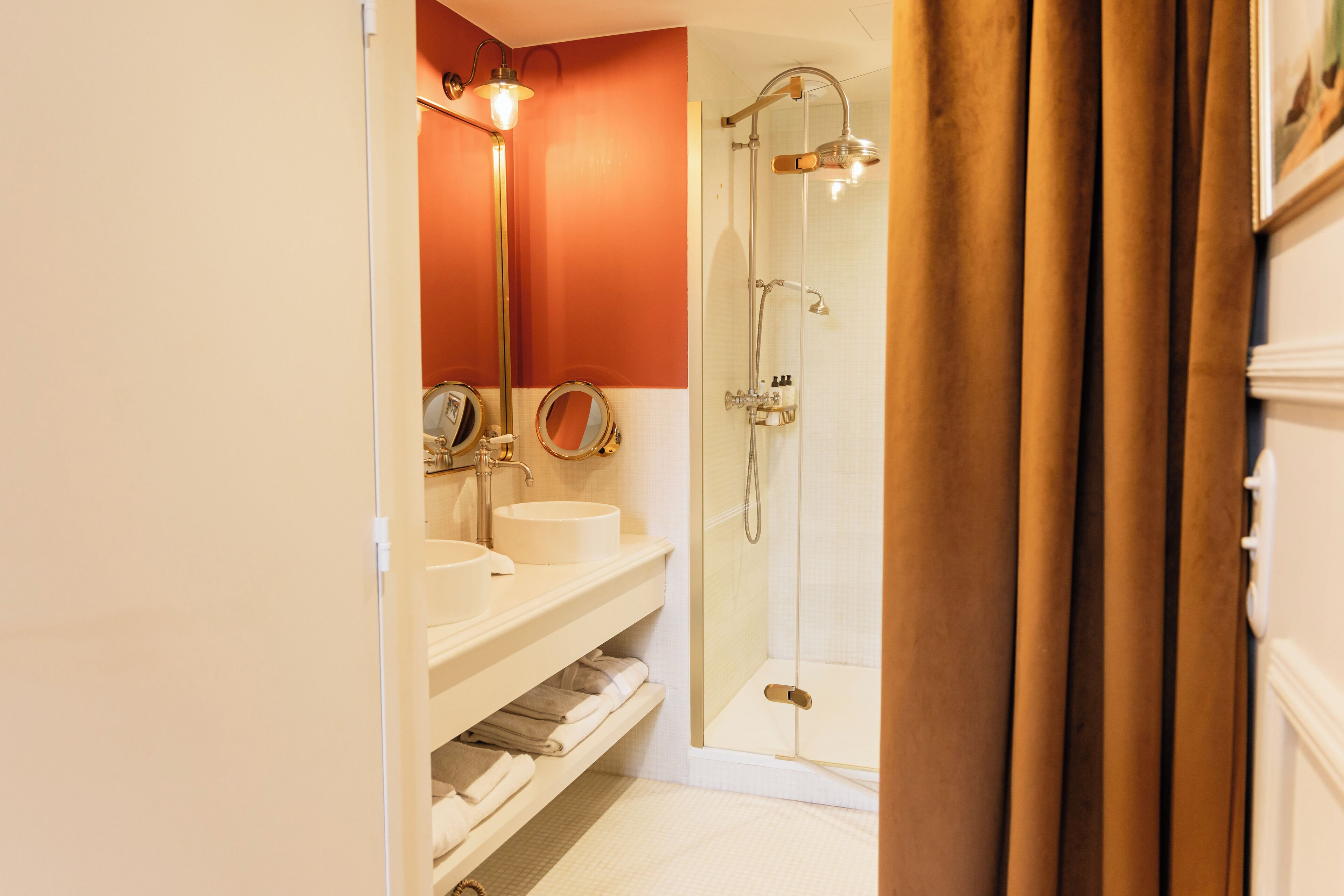 A bathroom with two sinks, a mirror, and a glass-enclosed shower.