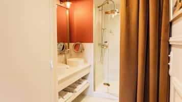 A bathroom with two sinks, a mirror, and a glass-enclosed shower.