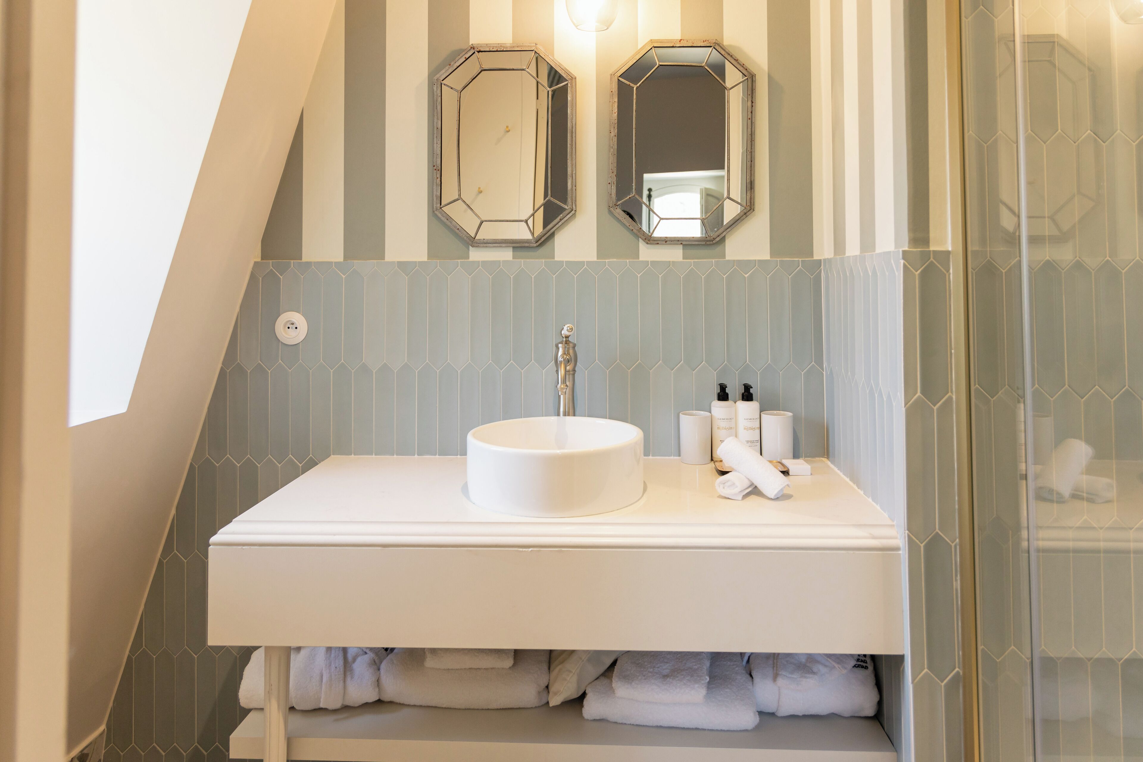 A bathroom with a white sink, two mirrors, and a towel rack.