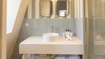 A bathroom with a white sink, two mirrors, and a towel rack.