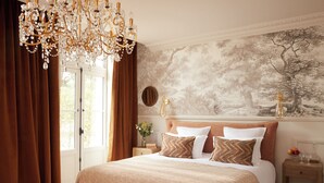 A bedroom with a large bed, a chandelier, a nightstand, and a wall mural. - Château Léognan, Domaine viticole - proche Bordeaux (Leognan)