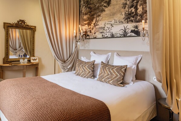A neatly made bed with a patterned throw, a mirror with a decorative frame, and a wall tapestry. - Château Léognan, Domaine viticole - proche Bordeaux (Leognan)