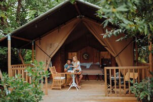 Alojamiento en carpa con terraza de madera, mesa y sillas.