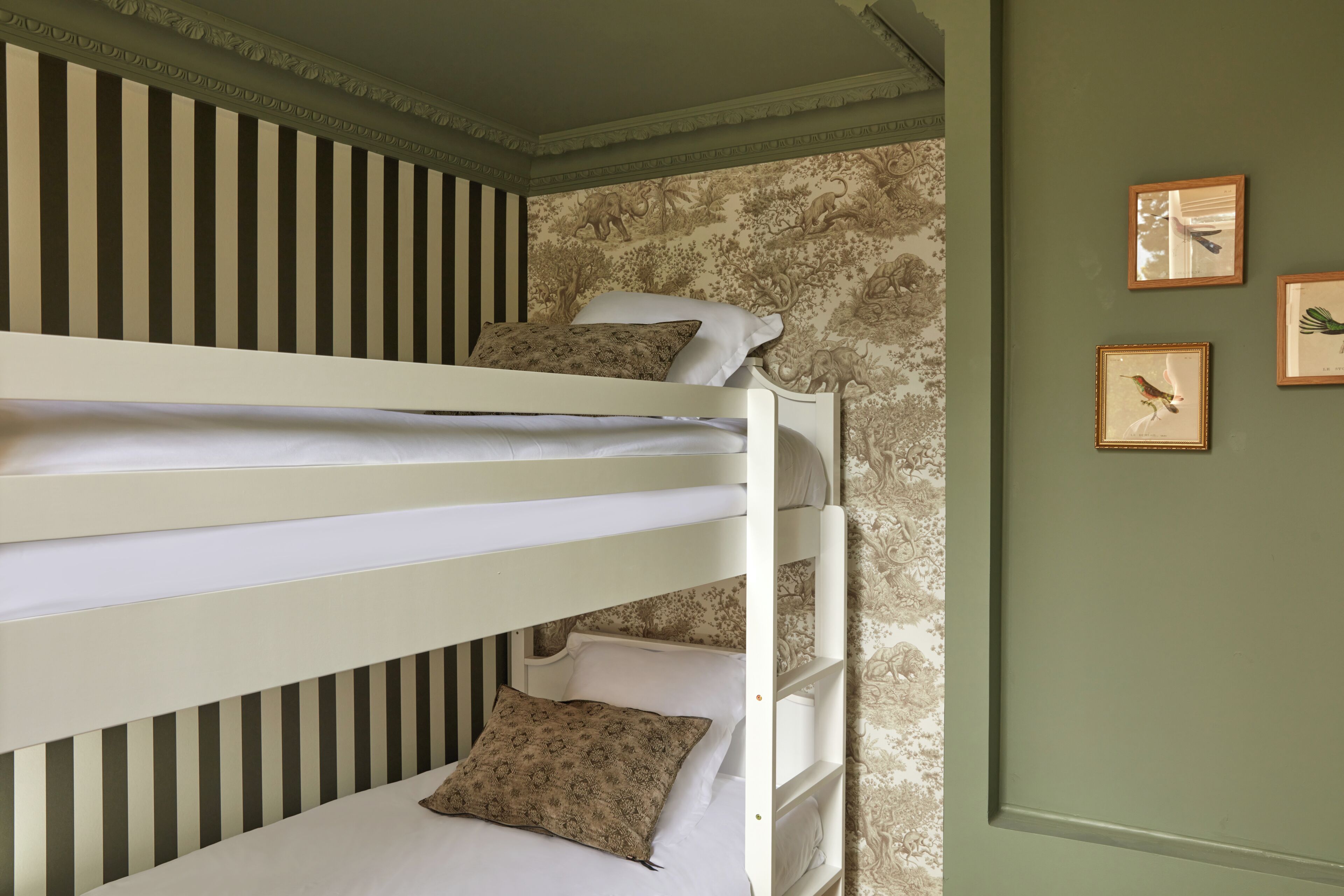 A bunk bed room with striped wallpaper and a floral-patterned wall.
