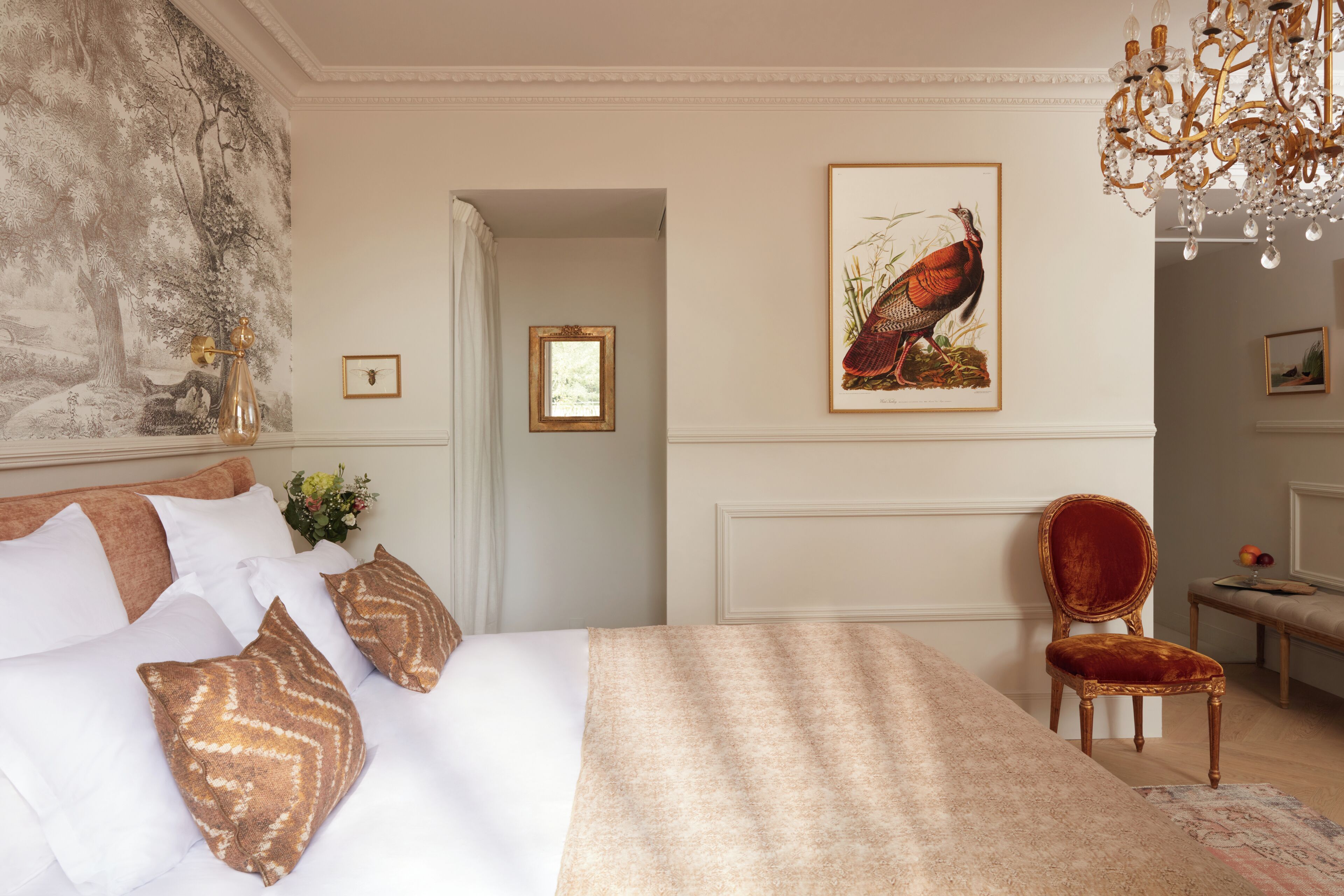 A well-appointed bedroom with a large bed, a chandelier, and framed artwork on the walls.