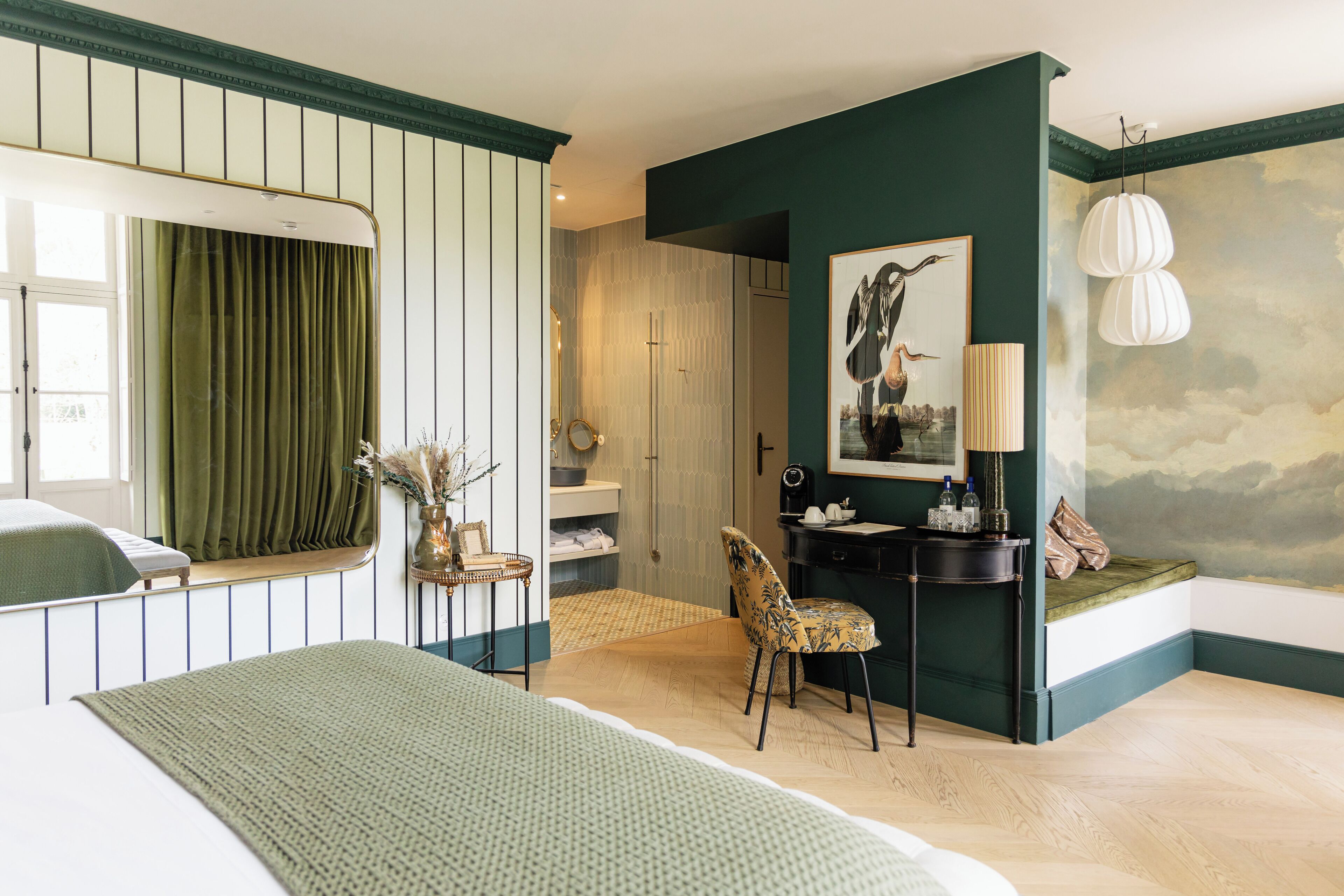 A bedroom with a bed, a chair, a desk, a mirror, and a painting on the wall.