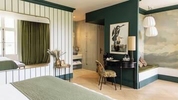 A bedroom with a bed, a chair, a desk, a mirror, and a painting on the wall.