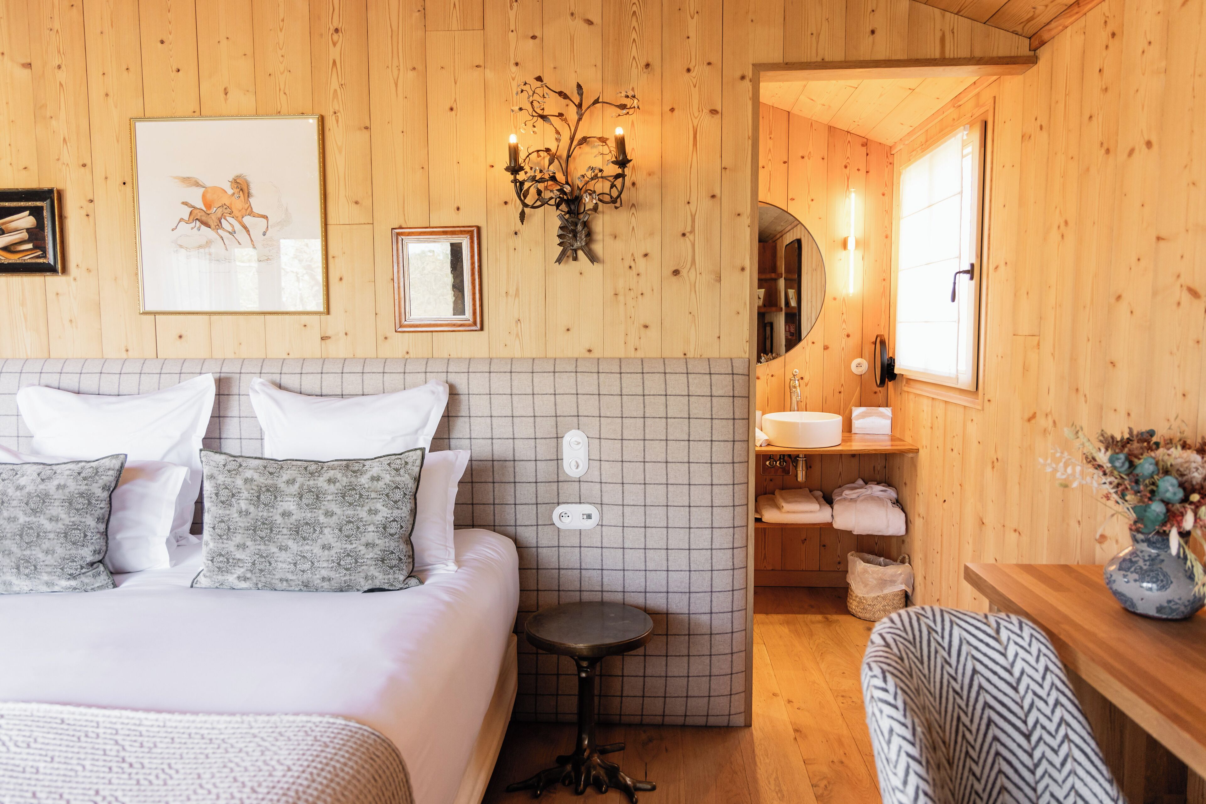 Una habitación acogedora de madera con una cama, una mesita redonda y una silla.