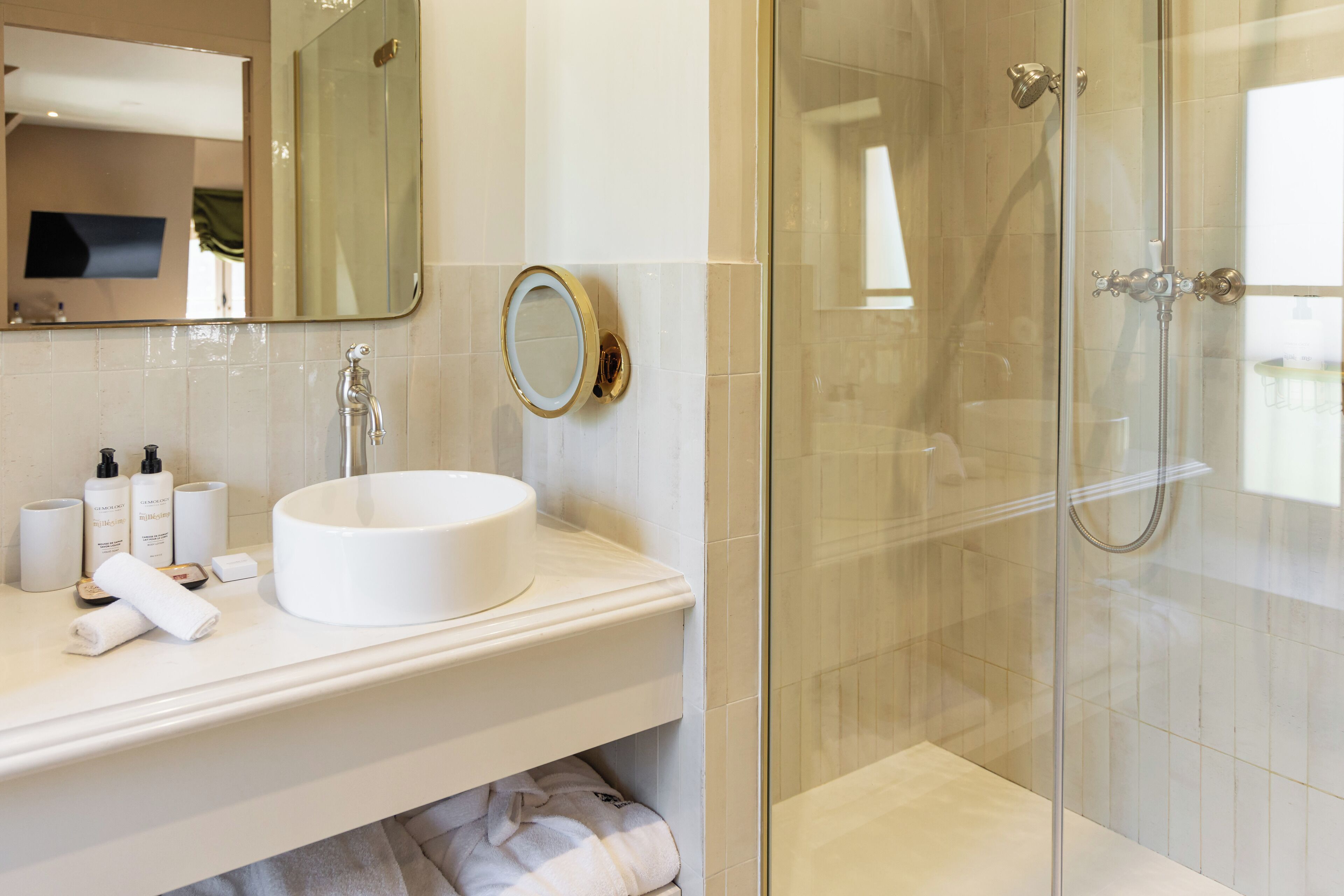 A bathroom with a white sink, a large mirror, and a glass-enclosed shower.