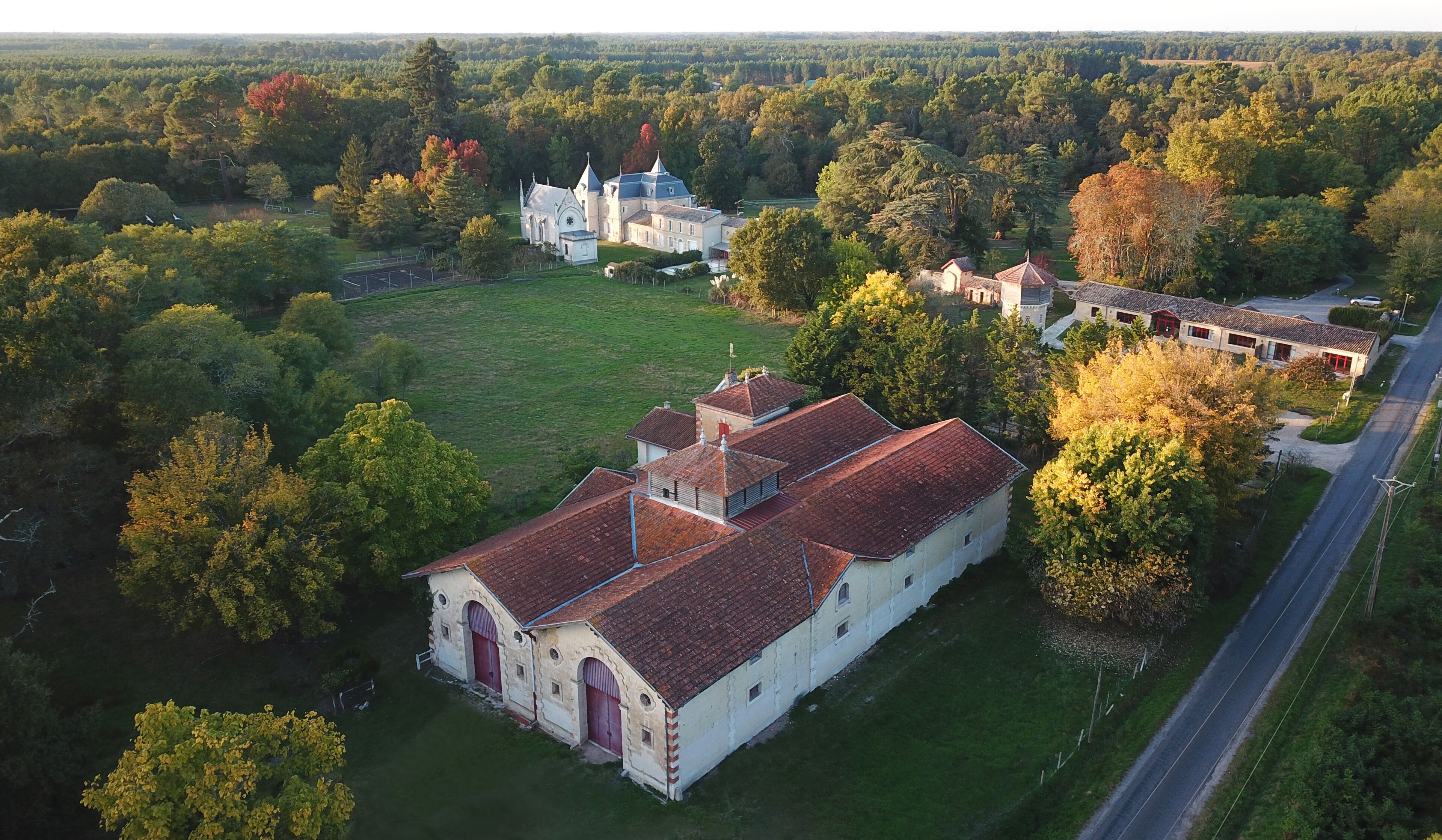 Vista aérea de uma grande propriedade com um edifício principal com telhado de telhas vermelhas e uma igreja com torre pontiaguda.