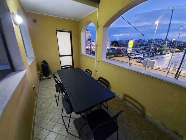 Un balcon avec une table et des chaises, une vue sur un parking et un bâtiment en arrière-plan.