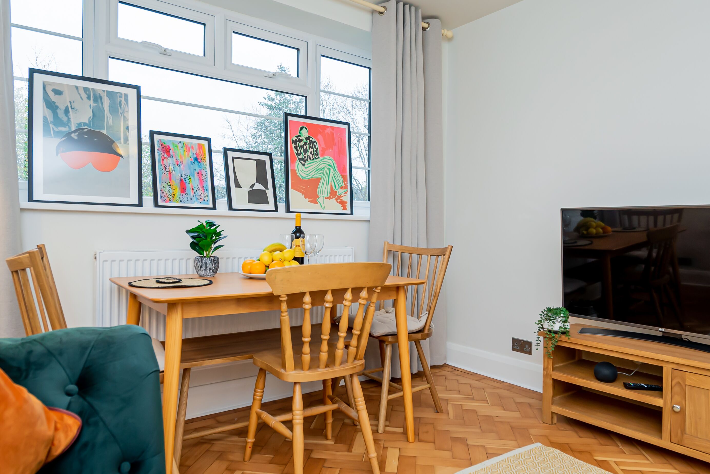 A dining area with a wooden table, chairs, and a TV on a wooden stand.