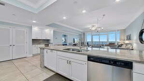 Una cocina moderna con armarios blancos, lavavajillas integrado y una isla grande con fregadero.