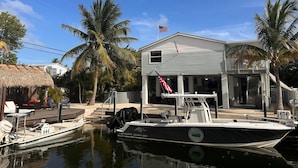 A house with a dock, a boat, and palm trees. - SOUTHERN SUNSET - As seen on House Hunters-S228 E6 - Family Time in the FL Keys (Cudjoe Key)