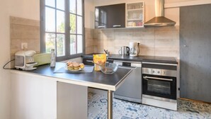 A modern kitchen with a large window, a coffee maker, a toaster, and a bag of flour on the counter. - Chante Cigale by Interhome (Mimizan)