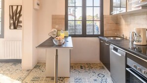 A compact kitchen with a window, a small table with a bowl and a bottle, and a dishwasher. - Chante Cigale by Interhome (Mimizan)