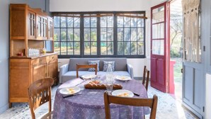 A dining area with a round table set for breakfast, a wooden cabinet, and a window with a view of the outdoors. - Chante Cigale by Interhome (Mimizan)