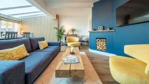 Un salon moderne avec un canapé, un fauteuil jaune et une table basse sur laquelle se trouve un magazine.