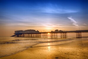 Un muelle que se adentra en el agua, con un atardecer al fondo.