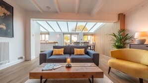 Un salon moderne avec un canapé, un fauteuil jaune et une table basse sur laquelle est posée une bougie.