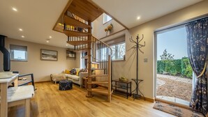 A spacious living area with a wooden staircase, a dining table, and a sofa. - Bumblebee Cottage, Culford Heath, Suffolk (Bury St Edmunds)