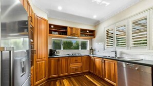 Una cocina moderna con armarios de madera, electrodomésticos de acero inoxidable y un amplio ventanal con persianas.