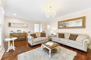A living room with a sofa, coffee table, wooden cabinet, and a chandelier.