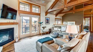A spacious living room with a fireplace, a large television, and a cozy seating area. - The Lodges D-1 - 1 Block to the Beach! (Cannon Beach)