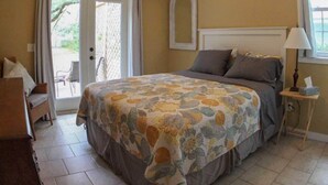 A bedroom with a bed, a ceiling fan, a window, and a door leading to a balcony. - Pet-friendly Cottage in the Trees - GREAT location! (Fernandina Beach)