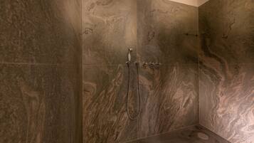 A shower with a handheld showerhead and a wall-mounted faucet.