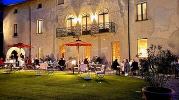 Un edificio con patio, mesas al aire libre y una entrada bien iluminada.