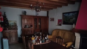 Ein Essbereich mit Holztisch, Stühlen, einer Pendelleuchte, einem Schrank und einer Couch.