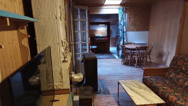 Ein gemütliches Zimmer mit Holzboden, einer Couch, einem Tisch und einem Fernseher.
