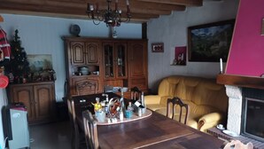 Ein Essbereich mit Holztisch und Stühlen, einer Kristallleuchter, einem Schrank mit Glastüren, einer Couch und einem Kamin.