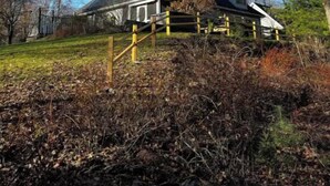 Una casa con techo inclinado, rodeada de árboles y una cerca.
