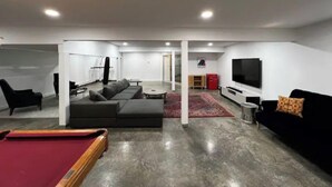 Una sala de estar moderna con mesa de billar, sofá, televisor y saco de boxeo.