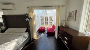 Un dormitorio con cama, cómoda y vista a una silla roja en el exterior.