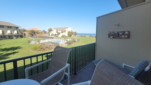 A balcony with a view of a pool, lounge chairs, and a building in the background. - SH 149.Ocean View Townhouse with great pool and ocean view. (St. Augustine)