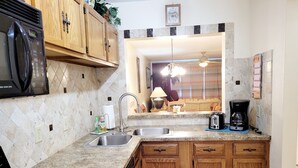 A kitchen with granite countertops, wooden cabinets, a built-in microwave, a stove, a sink, and a coffee maker. - SH 149.Ocean View Townhouse with great pool and ocean view. (St. Augustine)