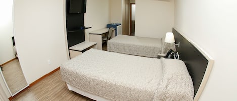 Habitación de hotel con dos camas, un escritorio, una silla, un televisor y aire acondicionado.